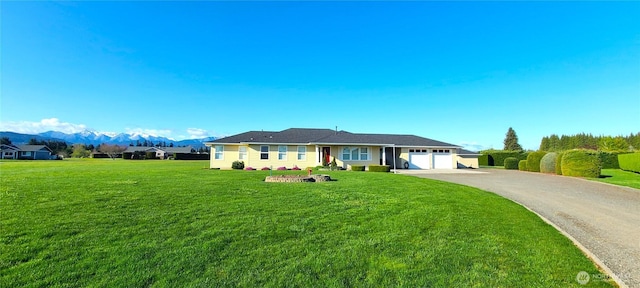 ranch-style house with an attached garage, driveway, a front lawn, and a mountain view
