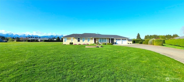view of front of home with an attached garage, a front lawn, aphalt driveway, and a mountain view