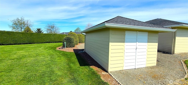 view of property exterior featuring fence, a shingled roof, an outdoor structure, a yard, and a shed