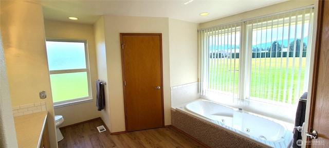 bathroom featuring wood finished floors, a jetted tub, toilet, vanity, and visible vents