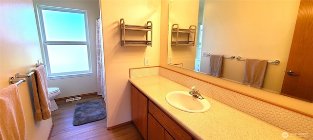 bathroom featuring toilet, vanity, wood finished floors, and visible vents