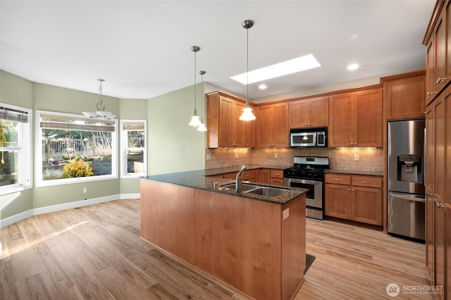 8148 Quinault Rd, Blaine, WA 98230 - kitchen featuring appliances with stainless steel finishes, backsplash, brown cabinetry, a skylight, and a sink