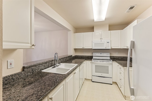 kitchen featuring dark stone countertops, white appliances, white cabinets, visible vents, and a sink