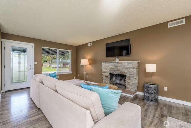 living area featuring a textured ceiling, wood finished floors, and visible vents
