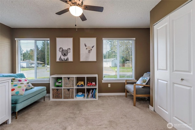 game room featuring a healthy amount of sunlight, ceiling fan, light colored carpet, and a textured ceiling
