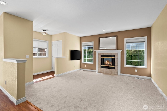 unfurnished living room with a wealth of natural light, carpet flooring, and baseboards