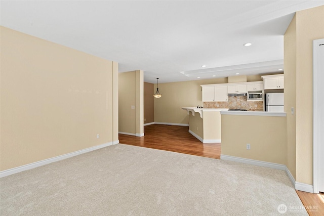 unfurnished living room featuring baseboards, light carpet, and recessed lighting