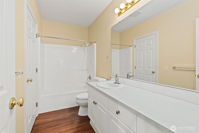 bathroom with toilet, vanity, wood finished floors, and tub / shower combination