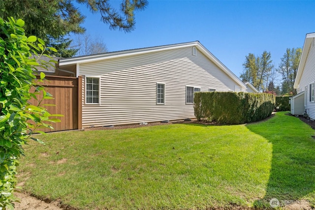 view of side of property with a lawn and fence