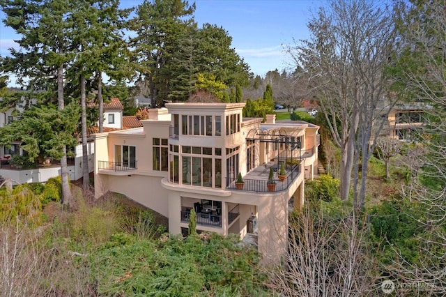 back of property with a balcony and stucco siding