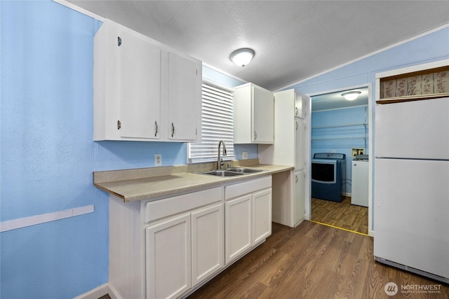 kitchen featuring freestanding refrigerator, white cabinets, dark wood finished floors, washer and dryer, and a sink