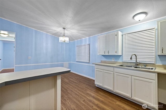 kitchen featuring pendant lighting, ornamental molding, white cabinetry, a sink, and dark wood-style floors