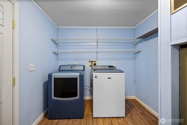washroom featuring laundry area, wood finished floors, baseboards, and washer and clothes dryer