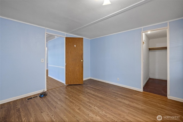 unfurnished bedroom with wood finished floors, baseboards, and visible vents