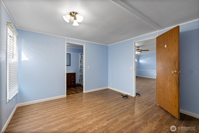 spare room featuring wood finished floors, ceiling fan, baseboards, and plenty of natural light