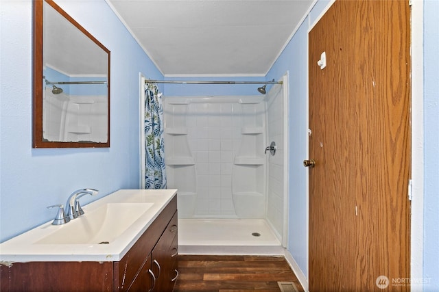 full bathroom with a shower with shower curtain, vanity, crown molding, and wood finished floors