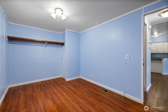 unfurnished bedroom with visible vents, crown molding, and wood finished floors