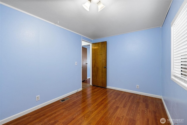 spare room featuring visible vents, baseboards, a ceiling fan, and wood finished floors