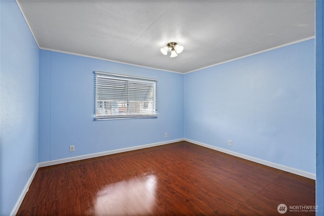 empty room featuring dark wood-style flooring, baseboards, and ornamental molding
