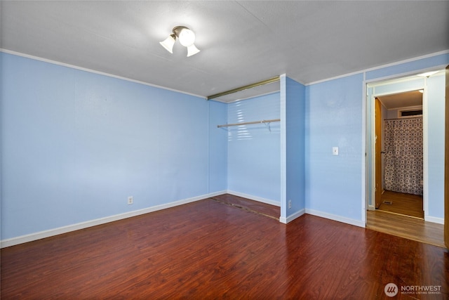 unfurnished bedroom with crown molding, wood finished floors, baseboards, and a closet