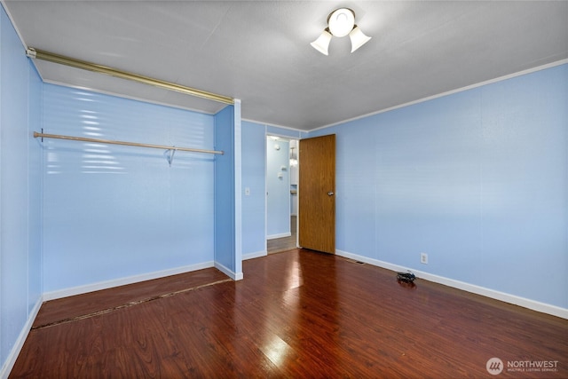 unfurnished bedroom featuring wood finished floors, a closet, ornamental molding, and baseboards