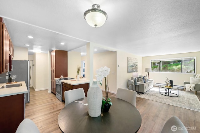 dining area with a textured ceiling, light wood-style floors, baseboards, and recessed lighting