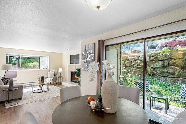 dining area with wood finished floors, a fireplace, and a baseboard heating unit