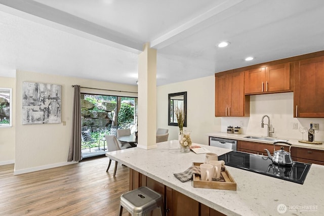 kitchen with light wood-style flooring, stainless steel dishwasher, brown cabinetry, a sink, and black electric stovetop