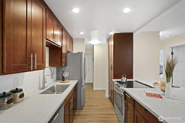 kitchen featuring light stone countertops, light wood-style flooring, recessed lighting, a sink, and appliances with stainless steel finishes