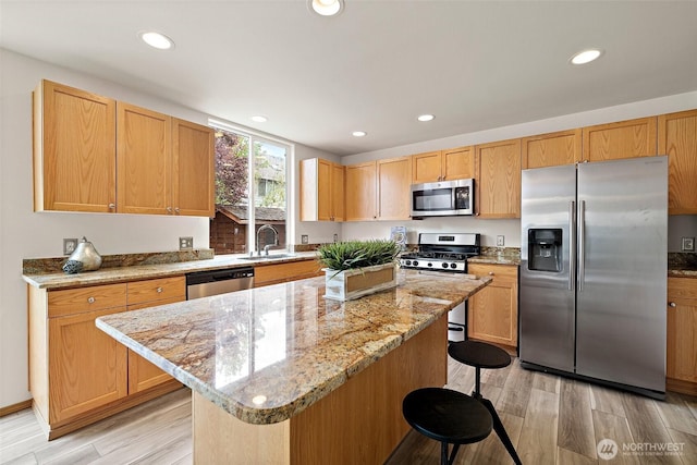 kitchen with stainless steel appliances, a sink, a kitchen bar, recessed lighting, and a kitchen island
