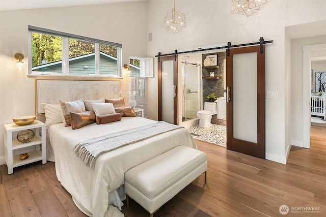 11820 NE 145th St, Kirkland, WA 98034 - bedroom with high vaulted ceiling, a barn door, ensuite bathroom, wood-type flooring, and baseboards