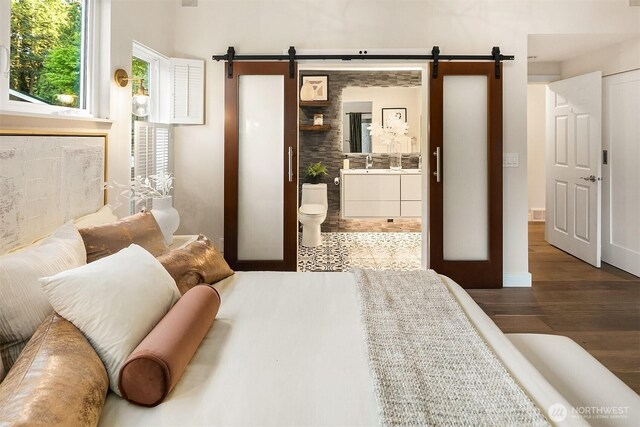 11820 NE 145th St, Kirkland, WA 98034 - bedroom featuring a barn door, ensuite bath, wood finished floors, and a sink