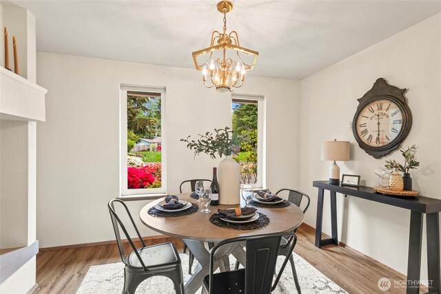 dining space with baseboards, light wood-type flooring, and a chandelier