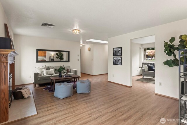 living area featuring visible vents, light wood finished floors, and baseboards