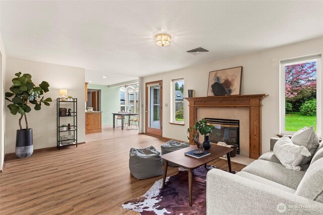 living area with visible vents, light wood-type flooring, a tile fireplace, and a wealth of natural light