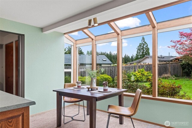 sunroom / solarium featuring a skylight, a textured wall, and carpet flooring