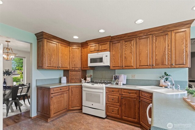 kitchen featuring white appliances, recessed lighting, light countertops, brown cabinets, and a sink