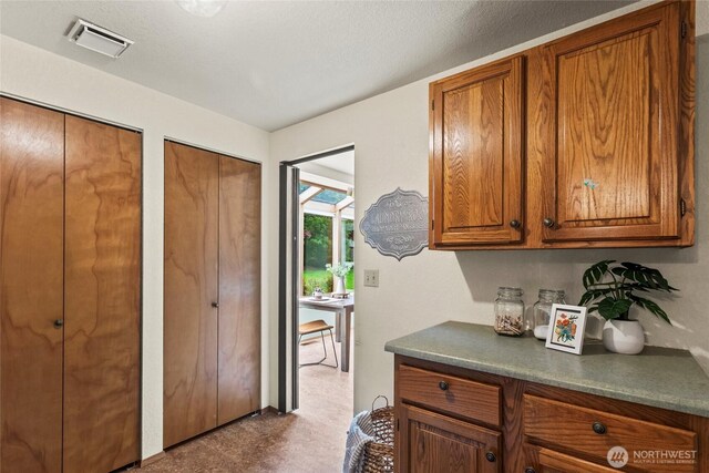 kitchen featuring dark countertops, brown cabinetry, and visible vents