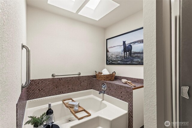 bathroom with a skylight and a garden tub