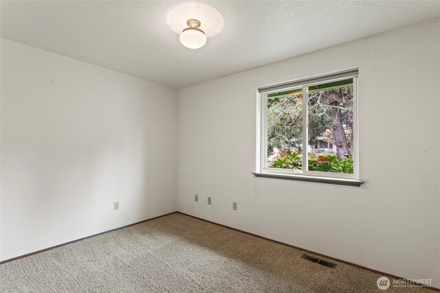empty room with baseboards, light carpet, and visible vents