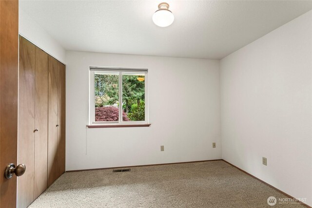 unfurnished bedroom featuring baseboards, visible vents, carpet, and a closet