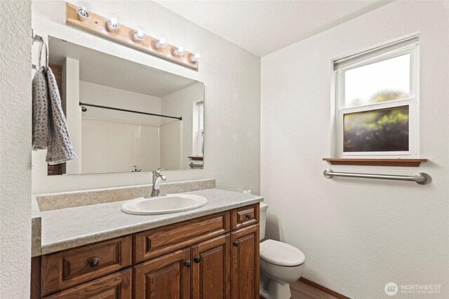 bathroom with toilet, wood finished floors, and vanity