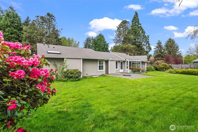 rear view of property featuring a lawn, a patio, and fence