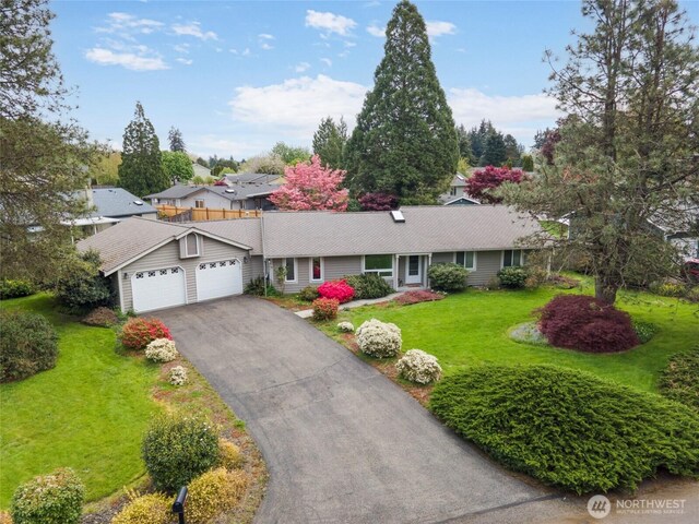 ranch-style house featuring an attached garage, driveway, and a front yard