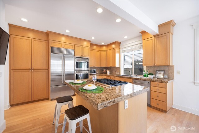 7018 117th Pl NE, Kirkland, WA 98033 - kitchen with a center island, a sink, appliances with stainless steel finishes, light wood-style floors, and decorative backsplash