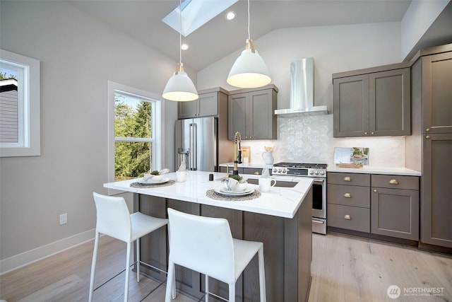 428 20th Ave, Kirkland, WA 98033 - kitchen featuring wall chimney exhaust hood, appliances with stainless steel finishes, a skylight, tasteful backsplash, and light wood finished floors