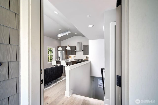 428 20th Ave, Kirkland, WA 98033 - kitchen with light wood-type flooring, lofted ceiling, wall chimney exhaust hood, light countertops, and a kitchen island with sink