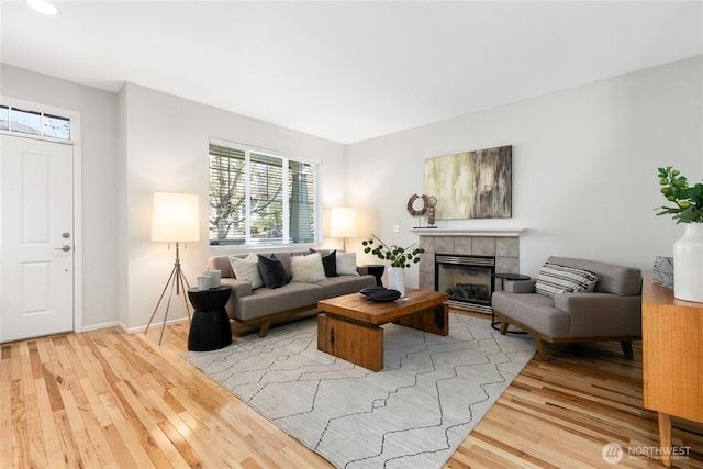 living room featuring a fireplace, baseboards, a wealth of natural light, and light wood-style floors
