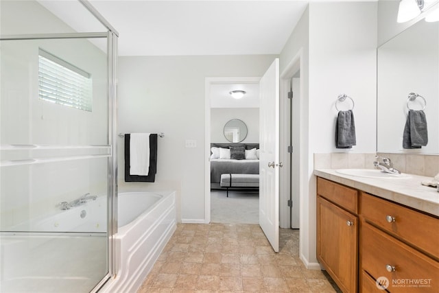 ensuite bathroom with connected bathroom, vanity, baseboards, a stall shower, and a garden tub