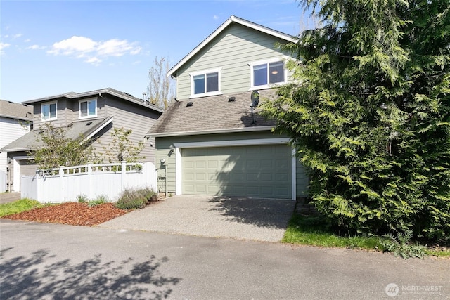 view of front of house with fence, aphalt driveway, and an attached garage